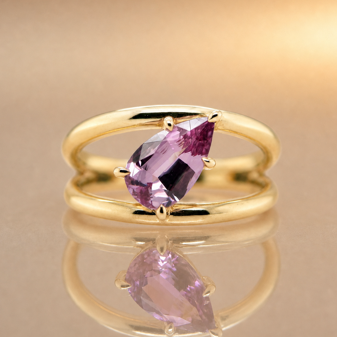 Gold ring with a purple gemstone on a reflective surface with a beige background